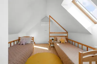 a attic room with two beds and a staircase at Statek Luigi in Tuchlovice
