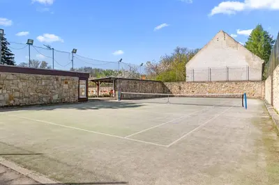 a tennis court with a stone wall at Statek Luigi in Tuchlovice