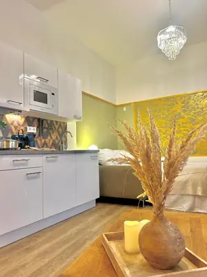 a kitchen with white cabinets and a vase on a table at Homely Nook Prague Centre in Prague