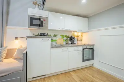 a kitchen with white cabinets and a couch in a room at HOMELY I Central 52m2 APT I ELEVATOR I Self Check-In in Prague