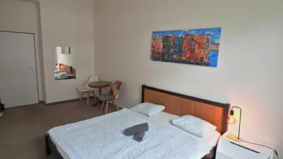 a bedroom with a bed and a table and a painting at Zizkov Stay - Near City Center in Prague