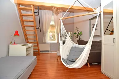 a hammock in a room with a bed and a ladder at Cozy Apartment in Letná in Prague