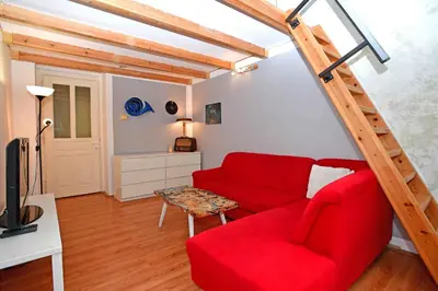 a living room with a red couch and a ladder at Cozy Apartment in Letná in Prague