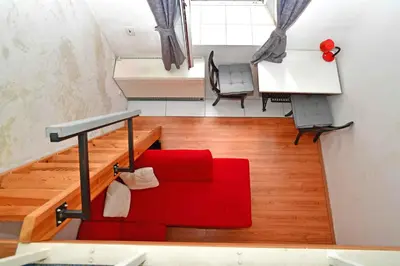 a living room with a red couch and stairs at Cozy Apartment in Letná in Prague