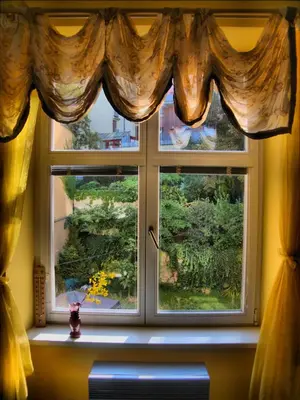 a window with curtains and a vase on a window sill at Stela's Apartments - Vysehrad in Prague