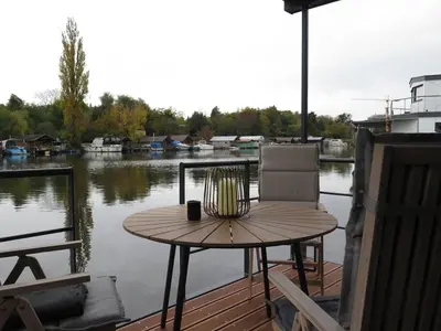 a table and chairs on a deck with a view of the water at Houseboat Rosie in Prague