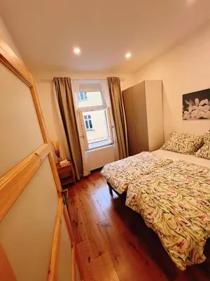 a living room with a vase of flowers on a wooden floor at Phuong'Nest Modern Apartment near Old Town in Prague