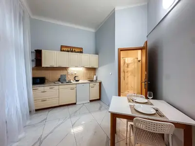 a kitchen with white cabinets and a table with chairs at MIVA apartments in Prague