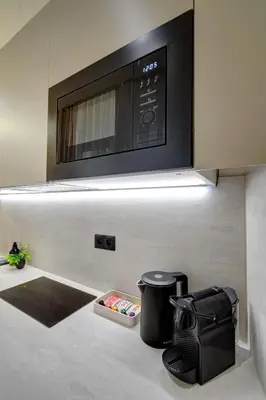a microwave above a kitchen counter with a trash can at CityMood Prague Apartment in Prague