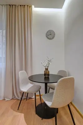 a dining room with a table and chairs and a clock at CityMood Prague Apartment in Prague