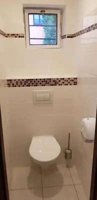 a white bathroom with a toilet and a window at Pension & Restaurace Na Rychtě in Prague