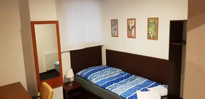 a small bedroom with a bed and a mirror at Pension & Restaurace Na Rychtě in Prague