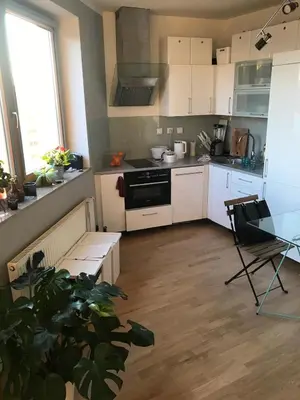 a kitchen with white cabinets and a table and a stove at COSY&SUNNY flat, center 10min, park 3min, baby cot, free weekend parking in Prague