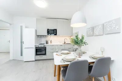 a white kitchen with a white table and chairs at Rentero Warm & Cozy Stay in Prague, By the River in Prague