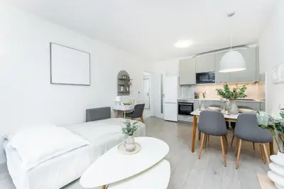 a white living room with a white couch and a table at Rentero Warm & Cozy Stay in Prague, By the River in Prague