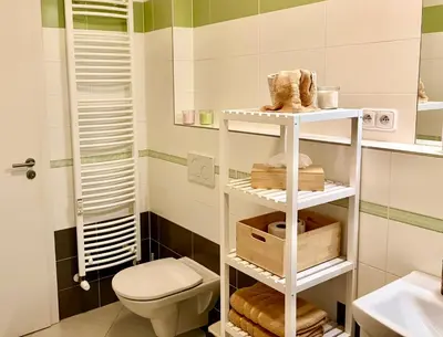 a bathroom with a toilet and a shelf with towels at My Sweet Home - Zakšínská - Prague in Prague