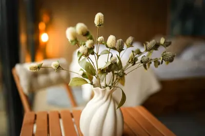 a white vase with flowers in it on a table at ermiglamping in Jince
