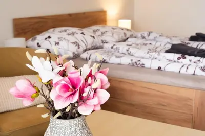 a vase with pink flowers on a table next to a bed at Apartmán IRIS Poděbrady 2 in Poděbrady
