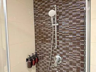 a shower in a bathroom with a tile wall at Serene Apartment near Wenceslas Sq & Main Station in Prague