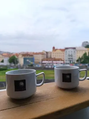 two white coffee cups sitting on a window sill at GeraStay Perucka in Prague