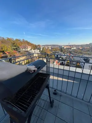 a person is holding a grill on a balcony at GeraStay Perucka in Prague