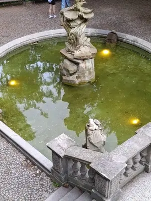 a small pond with a statue in a garden at GeraStay Perucka in Prague
