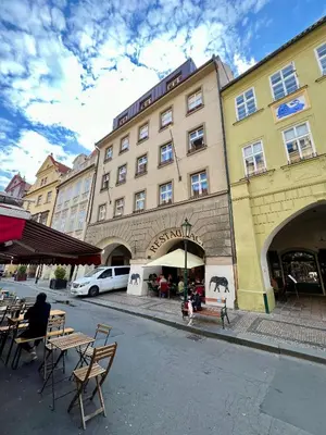 a building with tables and chairs in front of a street at Residence I at Havel's Market in Prague