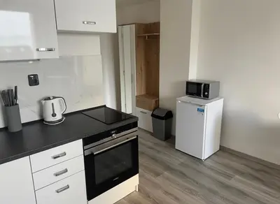 a small kitchen with a black counter top and a refrigerator at NEW beautiful apartment 15 minutes from the city center in Prague