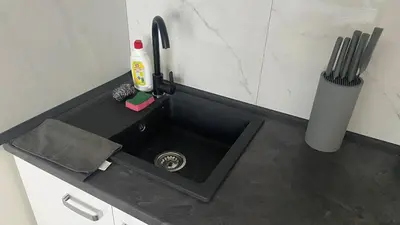 a kitchen counter with a black sink with a bottle at NEW beautiful apartment 15 minutes from the city center in Prague