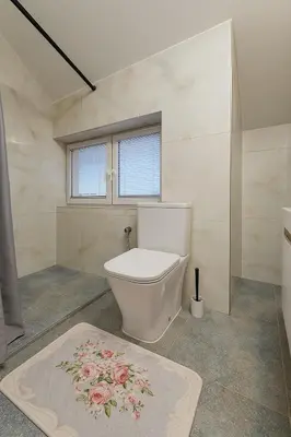 a bathroom with a toilet and a flower rug at KindStay Suite w Free Parking near Prague Airport in Tuchoměřice