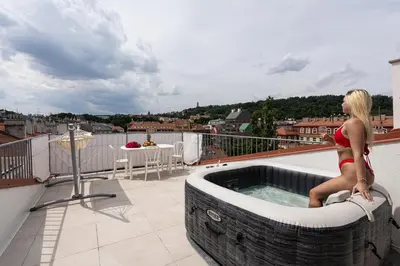 a woman sitting in a hot tub on a balcony at Royal Skyline Penthouse in Prague