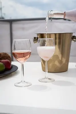 two wine glasses on a counter withwine being poured into it at Royal Skyline Penthouse in Prague