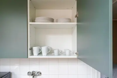 a cupboard with cups and saucers in it at Blueground Anděl view nr Vltava River PRG-80 in Prague