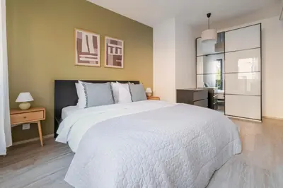 a bedroom with a large white bed and a kitchen at Blueground Žižkov balcony nr Vítkov Hill PRG-82 in Prague