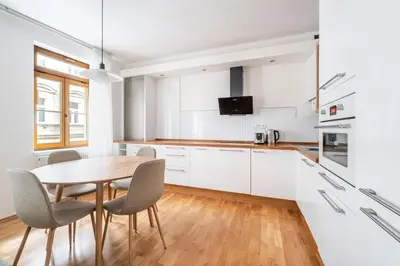 a kitchen with white cabinets and a table and chairs at Blueground Vršovice view nr Havlíčkovy sady PRG-81 in Prague