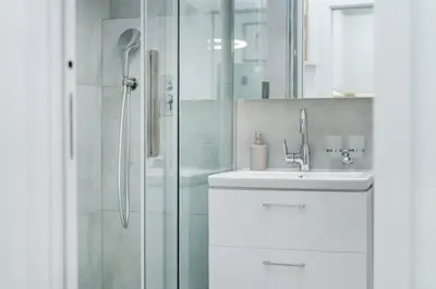 a white bathroom with a shower and a sink at Rentero Warm and Bright Apartment at Prague in Prague