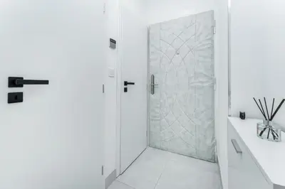 a white bathroom with a shower and a glass door at Rentero Warm and Bright Apartment at Prague in Prague