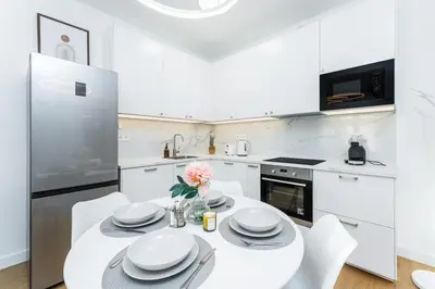 a white kitchen with a white table and chairs at Rentero Warm and Bright Apartment at Prague in Prague