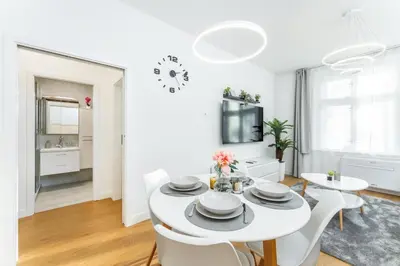 a white dining room with a white table and chairs at Rentero Warm and Bright Apartment at Prague in Prague