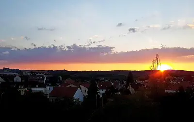 a sunset over a city with the sun in the sky at Veles Apartment in Prague