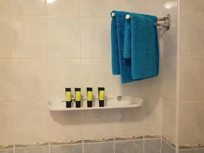 a bathroom with blue towels and a shelf with five candles at Veles Apartment in Prague