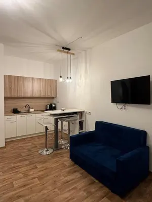 a living room with a blue couch and a kitchen at Diamond suite in Prague