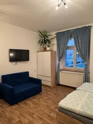 a living room with a blue couch and a window at Diamond suite in Prague