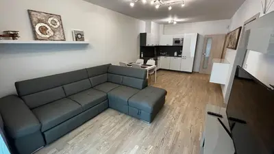 a living room with a blue couch and a kitchen at Residence Garden Tower - 8 min do centra, garaz in Prague