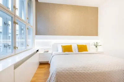 a white bedroom with a bed with yellow pillows at Residence near the Old Town Square in Prague