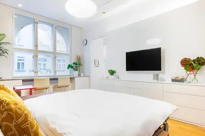 a white bedroom with a large bed and a flat screen tv at Residence near the Old Town Square in Prague