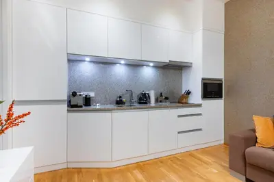 a white kitchen with white cabinets and a couch at Residence near the Old Town Square in Prague