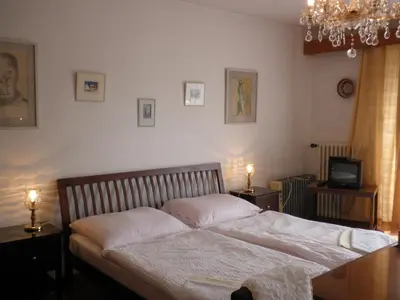 a bedroom with a bed with white sheets and a television at Pension Arcadia Prague in Prague