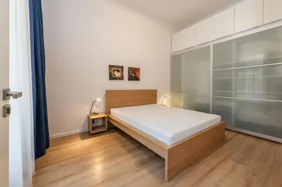 a bedroom with a bed with white walls and wooden floors at Apartment Vinohradská 14 in Prague