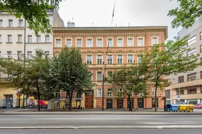 a large brick building with trees in front of a street at Apartment Vinohradská 14 in Prague